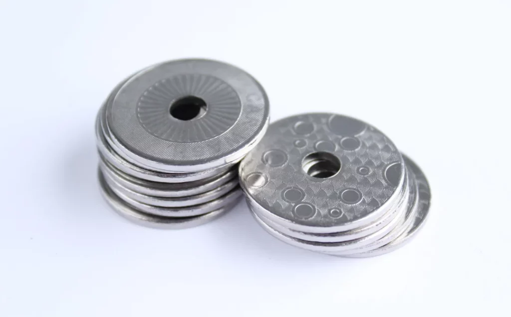 2 piles of all the same tokens. The right pile shows one side with a bubble design while the left shows the other side with a hardly visible latent images text "Car Wash"